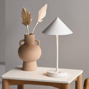 Modern Conical Portable Desk Lamp with white finish on a table next to a ceramic vase