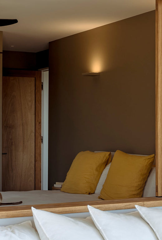 Modern bedroom with yellow pillows and a stylish wall mirror.