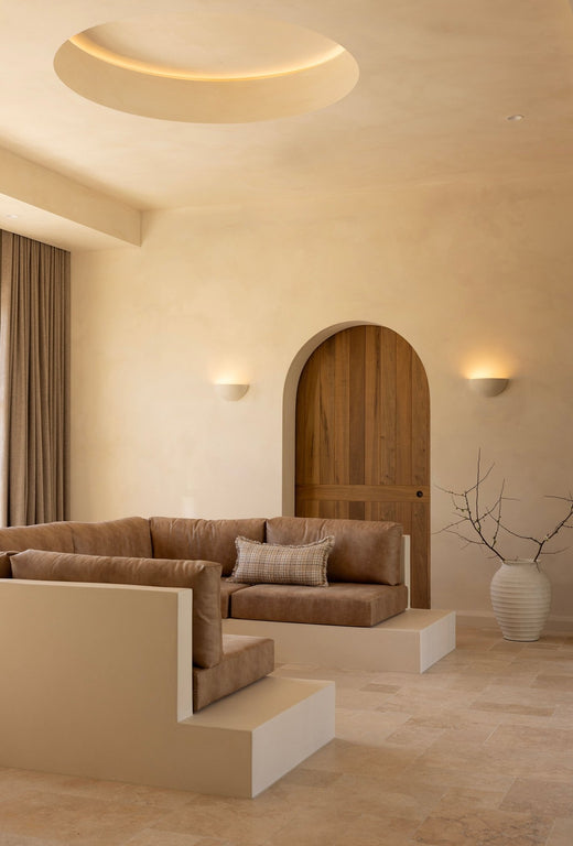 Modern living room with beige tones, curved furniture, and an arched door.
