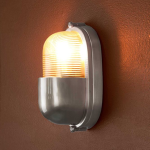 Oval Bunker Rib Glass and Brass Wall Light silver finish lit up in outdoor space