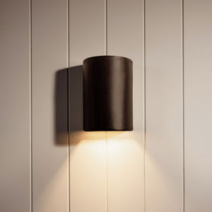 Handmade Exterior Shimmering Ceramic Wall Light slate lit up on a beige timber wall