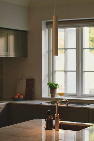 Modern kitchen with a sink and countertop, featuring the beige Reeded Metal Vertical Pendant - Lighting Collective 