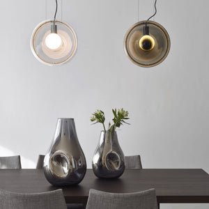 Mouth-Blown Glass Lenses Pendant Light black and clear finishes over a dining table front view
