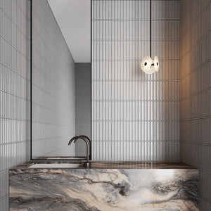 Coral Trio Drop Pendant Light bronze frosted lit up in a bathroom over a marble sink next to a mirror