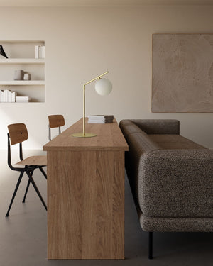 Modern interior with wooden desk, lamp, and sofa in a minimalistic setting.