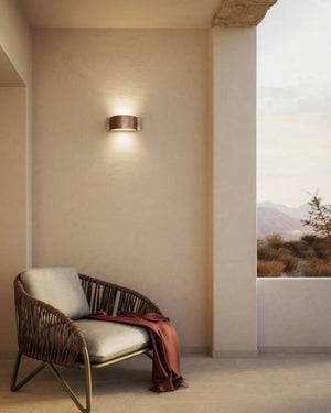 Antique Copper Arc Wall Light on a balcony over a rattan chair