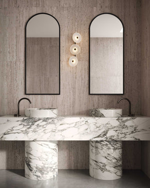 Bathroom with marble vanity, two arched mirrors, and wall sconces.