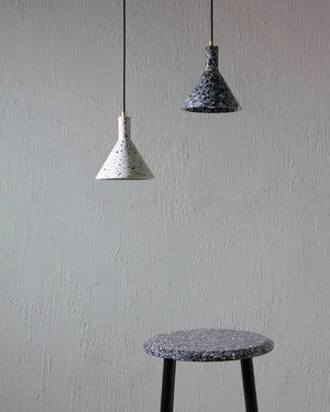 Two Terrazzo pendant lights hang above a stool with a matching design on a plain wall.