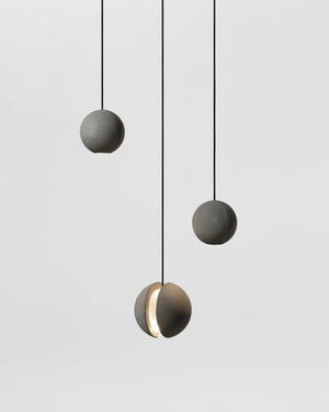 Three modern pendant lights hanging against a light gray background