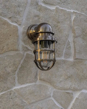 Brass Bunker Light Dark Brass installed on a stone wall | Lighting Collective
