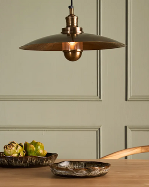 Cast Metal Disc Pendant over a dining table in front of a light green wall | Lighting Collective