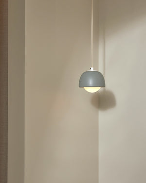 Gray pendant light hanging against a beige wall