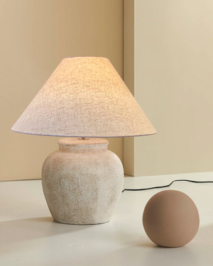 Table lamp with a textured shade and base on a neutral background