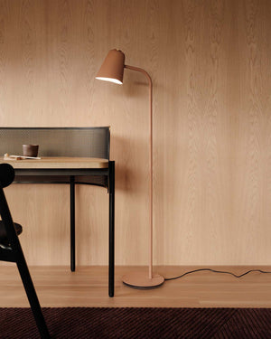 Modern floor lamp with a wooden desk and chair against a wooden wall.