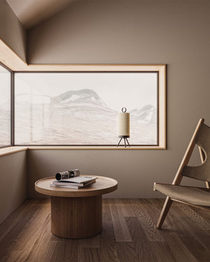 Modern interior with a round wooden table and chair in front of a large window with a mountain view.