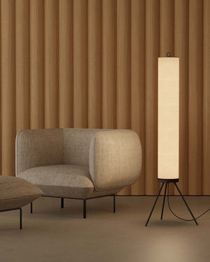 Modern beige armchair and floor lamp against a brown striped wall.