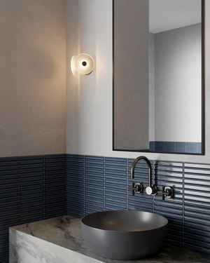 Modern bathroom with a dark grey sink, faucet, and blue tiled wall, glass wall light.