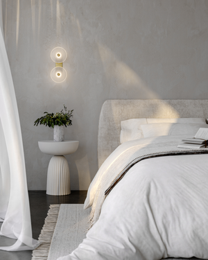 Modern bedroom with a bed, side table, and glass wall sconce.