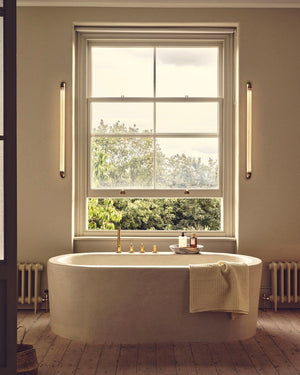 Modern bathroom with freestanding bathtub near a large window and Cylindrical Linear Bathroom Reeded Glass Wall Lights 