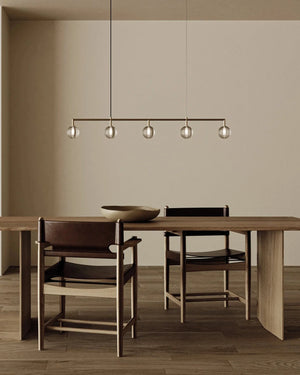 Dining area with wooden table and chairs, modern pendant light, and neutral wall.