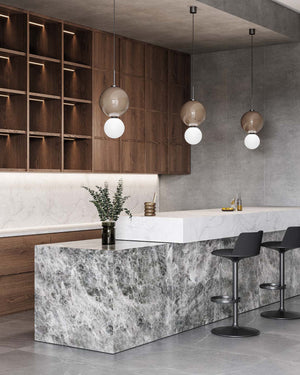 Modern kitchen with marble island, wooden cabinets, and double orb pendant lights with brown shades