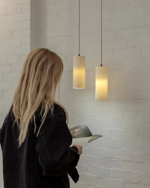 Person looking at pendant lights in a showroom with a white brick wall.