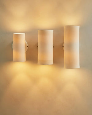 Three cylindrical ceramic Dusked Eos wall lights on a beige wall