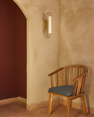 Wooden chair with a gray cushion against a textured wall with Elongated Fluted Glass Wall Light
