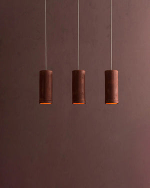 Three cylindrical pendant lights hanging against a brown background