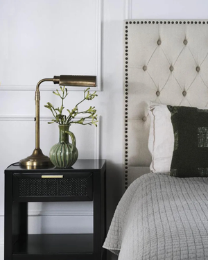 Nighstand with Gentlemen Desk Lamp and vase next to a bed with tufted headboard