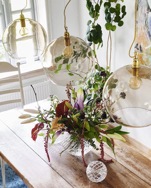 Decorative glass pendant lights hanging above a table with a floral arrangement.