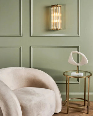 Modern beige armchair in a room with green paneled walls and a glass rods semicircular wall light