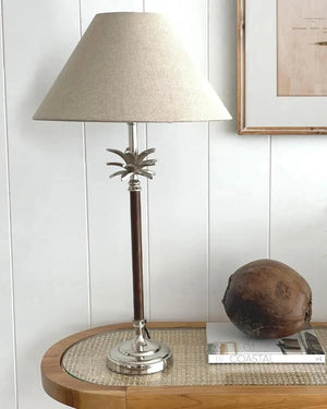 Table lamp with palm tree design on a wooden table against a white paneled wall | Lighting Collective