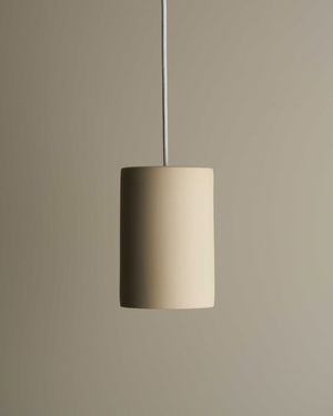Beige cylinder pendant light against a beige wall