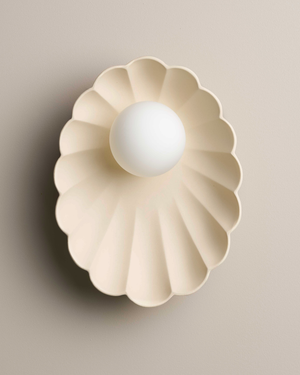 Decorative wall light fixture with a scalloped shell on a beige background