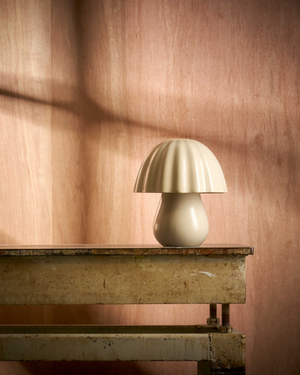 Table lamp with a decorative shade on a wooden surface against a wooden wall.