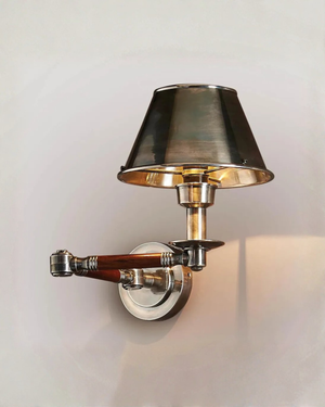 Wall-mounted lamp with a metallic shade and arm on a light gray background