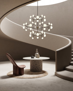 Modern chandelier hanging above a table and chair in a minimalistic room.