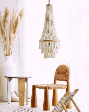 Beaded chandelier with a metal fixture and white beads installed above a side table