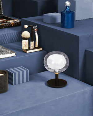 Glass sphere table lamp with black base on a blue background