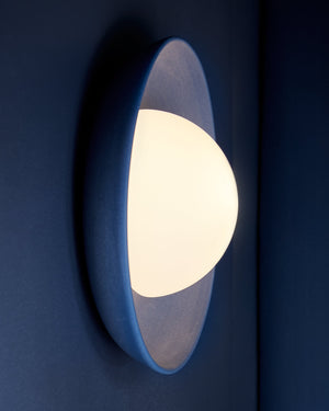 Lapis coloured wall-mounted Mani Wide sconce light fixture on a blue wall