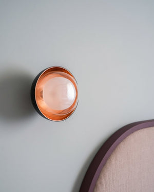 Round metal wall light on a light blue wall