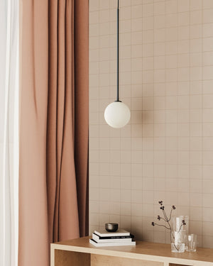 Modern interior with a pink curtain, pendant light, and small table with decor items.