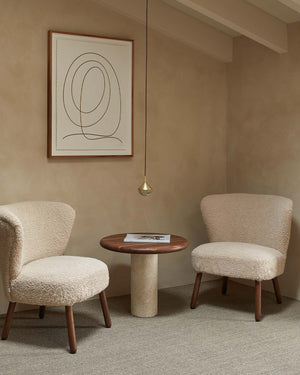 Minimalist Drop Suspended Pendant, two upholstered chairs with a small round table against a beige wall with a framed abstract painting.