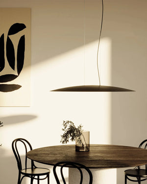Modern dining room with round wooden table and black chairs, featuring a Minimalist Mirrored Disc Pendant