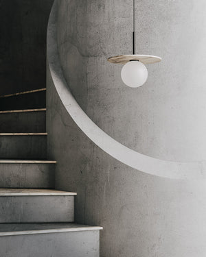 Modern pendant light hanging from a concrete ceiling with stairs in the background