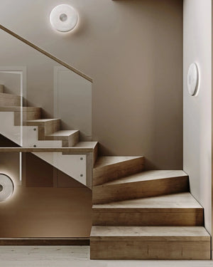 Modern staircase with wooden steps and glass balustrade in a neutral-colored room and Minimalist Perforated Disc Wall Sconces on the walls