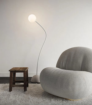 Minimalist Flexible Arm and Orb Floor Lamp in a living room with a grey arm chair and wooden stool