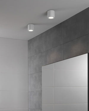 Two ceiling lights in a room with tiled walls and a mirror.