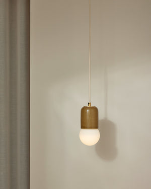 Pendant light with a mustard ceramic shade and white bulb on a neutral background
